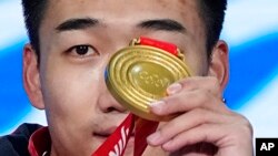 China's Gao Tingyu holds up gold medal during ceremonies for the men's 500-meter speedskating at the 2022 Winter Olympics in Beijing, Feb. 12, 2022.