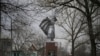 A woman walks with a child near a WWII memorial monument in Stanytsia Luhanska, eastern Ukraine, Feb. 11, 2022. The chill of a Cold War hung over Eastern Europe Friday, with Russian maneuvers and drills close to Ukraine.