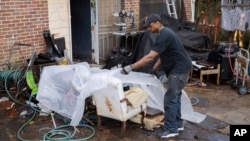 Prince Beatty covers up some chairs with a clear plastic cover to keep from getting wet on Monday, Jan. 10, 2022, in East Point, Ga.