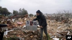 A Palestinian collects family photos in the ruins of a house demolished by Jerusalem municipal authorities, in the disputed Sheikh Jarrah neighborhood, Wednesday, January 19, 2022.