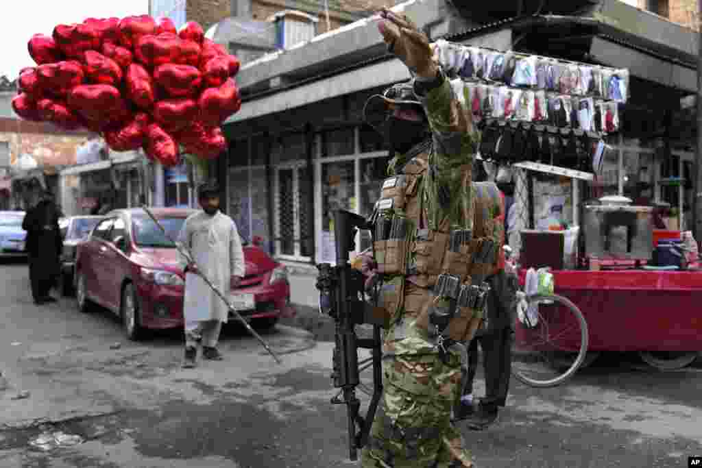 A Taliban fighter directs traffic as a street vendor sells red heart-shaped balloons for Valentine&#39;s Day, in Kabul, Afghanistan.