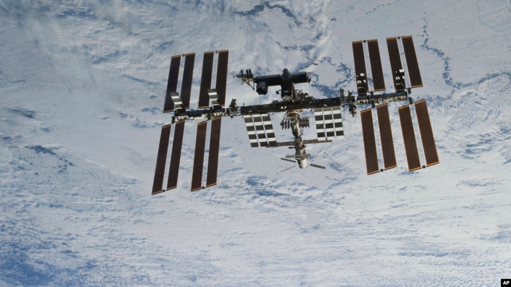 In this NASA photo, backdropped against clouds over Earth, the International Space Station is seen from Space Shuttle Discovery as the two orbital spacecraft accomplish their relative separation on March 7, 2011. (NASA via AP)