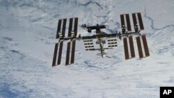 In this NASA photo, backdropped against clouds over Earth, the International Space Station is seen from Space Shuttle Discovery as the two orbital spacecraft accomplish their relative separation on March 7, 2011. (NASA via AP)