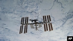 In this NASA photo, backdropped against clouds over Earth, the International Space Station is seen from Space Shuttle Discovery as the two orbital spacecraft accomplish their relative separation on March 7, 2011. (NASA via AP)