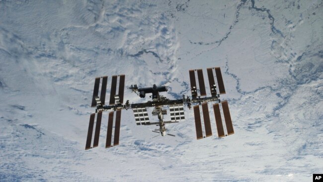 In this NASA photo, backdropped against clouds over Earth, the International Space Station is seen from Space Shuttle Discovery as the two orbital spacecraft accomplish their relative separation on March 7, 2011. (NASA via AP)