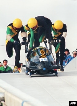 FILE - Jamaican four-man bobsled pilot Dudley Stokes jumps in as his three teammates push off at the start of the second run of the Olympic four-man bobsleigh event Feb. 27, 1988, at the Canada Olympic Park in Calgary.