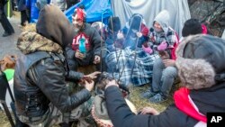 People demonstrating against COVID-19 restrictions stay warm with blankets and a fire during frigid temperatures on Wellington Street in the Parliament Hill area of Ottawa, Ontario, Canada, on Sunday, Feb. 13, 2022. (AP Photo/Ted Shaffrey)