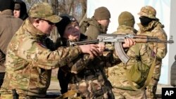 An instructor shows a woman how to use a Kalashnikov assault rifle, as members of a Ukrainian far-right group train, in Kyiv, Feb. 13, 2022.