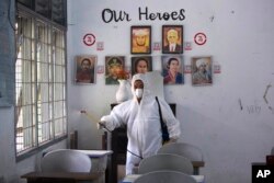 Seorang pekerja menyemprotkan disinfektan di dalam ruang kelas yang kosong setelah ditemukan kasus COVID-19 di sebuah sekolah di Medan, Sumatera Utara, Jumat, 11 Februari 2022. (Foto: AP)