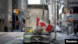 A parked truck with a Canadian flag upside down is seen, as truckers and supporters continue to protest COVID-19 vaccine mandates, in Ottawa, Ontario, Canada, Feb. 14, 2022. 