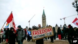 Don Stephens, 65, a retired graphic designer, holds a sign on Parliament Hill to support trucks lined up in protest of COVID-19 vaccine mandates and restrictions in Ottawa, Ontario, on Saturday, Feb. 12, 2022. (AP Photo/Ted Shaffrey)