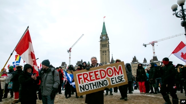 Don Stephens, 65, a retired graphic designer, holds a sign on Parliament Hill to support trucks lined up in protest of COVID-19 vaccine mandates and restrictions in Ottawa, Ontario, on Saturday, Feb. 12, 2022. (AP Photo/Ted Shaffrey)