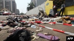 Warga berdiri di dekat pakaian dan barang-barang yang berserakan di jalanan sekitar stadion di kota Abidjan, Pantai Gading (1/1). Sedikitnya 60 orang dilaporkan tewas terinjak-injak saat berdesakan menyaksikan pertunjukan kembang api dalam perayaan Tahun Baru 2013 di sebuah stadion kota ini.