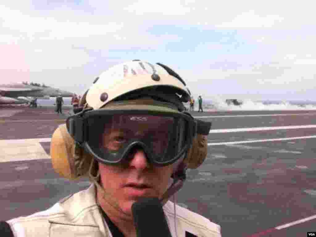 VOA Correspondent Steve Herman reporting from the windy flight deck of the USS George Washington as an F-18 fighter jet prepares to take off in the Yellow Sea, June 24, 2012.