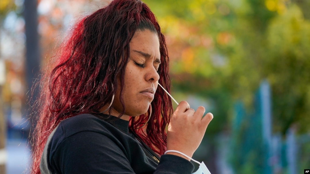 A resident uses a swab to take a coronavirus test at the Central Family Life Center, Nov. 10, 2020, in the Stapleton neighborhood of the Staten Island borough of New York. 