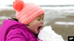 Emmaline Dendinger enjoys a big bite of snow as she plays in her Jackson, Mississippi neighborhood, Dec. 2017. (AP Photo/Rogelio V. Solis)