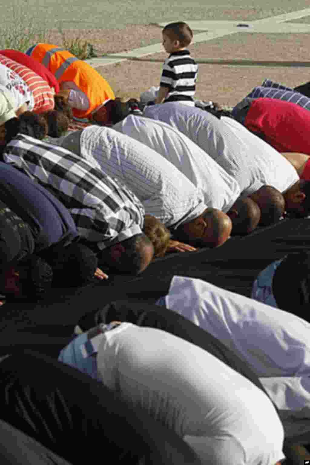 A boy stands among Muslim immigrants attending Eid al-Fitr prayers that mark the end of Ramadan in Athens, Greece, Aug. 30, 2011. AP