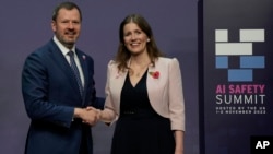 FILE - Britain's Secretary of State for Science, Innovation and Technology Michelle Donelan, right, shakes hands with Australia's Minister for Industry and Science Ed Husic, as he arrives at the AI Saftey Summit in Bletchley Park, Milton Keynes, England, Wednesday, Nov. 1, 2023. 