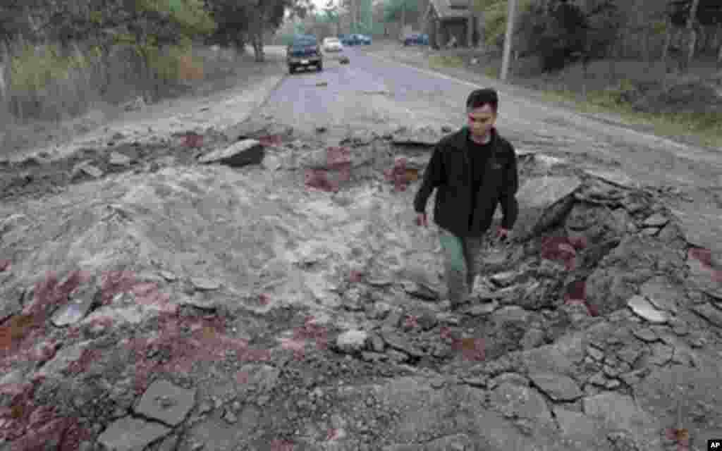 A Thai man walks though a bomb crater near Sisaket, Thailand, near the border with Cambodia, Monday, Feb. 7, 2011. Troops of Cambodia and Thailand continue to clash near the 11th century Preah Vihear temple.