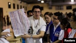 Un funcionario electoral muestra la papeleta de votación durante las elecciones municipales y legislativas de El Salvador.