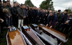 Relatives surround some of the coffins during the funeral of six members of the Cara family, killed during an earthquake that shook Albania, in Thumane, Albania, Nov. 29, 2019.