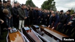 Relatives surround some of the coffins during the funeral of six members of the Cara family, killed during an earthquake that shook Thumane, Albania, Nov. 29, 2019.