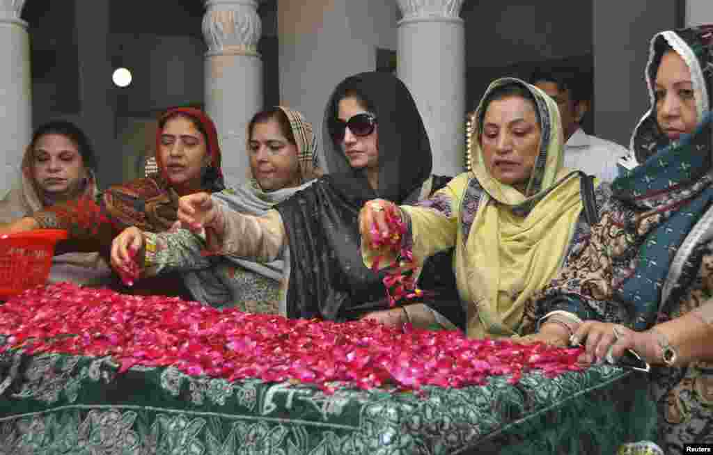 پاکستان پیپلز پارٹی کی کارکنان بے نطیر بھٹو کی قبر پر پھول نچھاور کر رہی ہیں