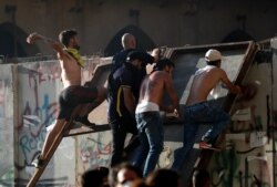 Anti-government protesters climb concrete wall that installed by security forces and throw stones against the army, as they try to reach the Parliament building, during a protest against the political elites and the government, Beirut, Aug. 8, 2020.