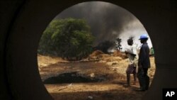 Workers, seen through a pipe, look on at the scene of an oil pipeline fire in Dadabili, Niger state. (File)