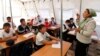 FILE - Children listen to their teacher during a lesson at a local school, based in a tent, in the city of Osh, Kyrgyzstan.