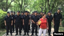 一名女子站在警戒线前，抗议子女的小学被重新划片。(2017年6月30日)