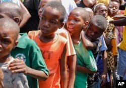 FILE— Children line up to receive a plate of food at a shelter for families displaced by gang violence, in Port-au-Prince, Haiti, March 14, 2024