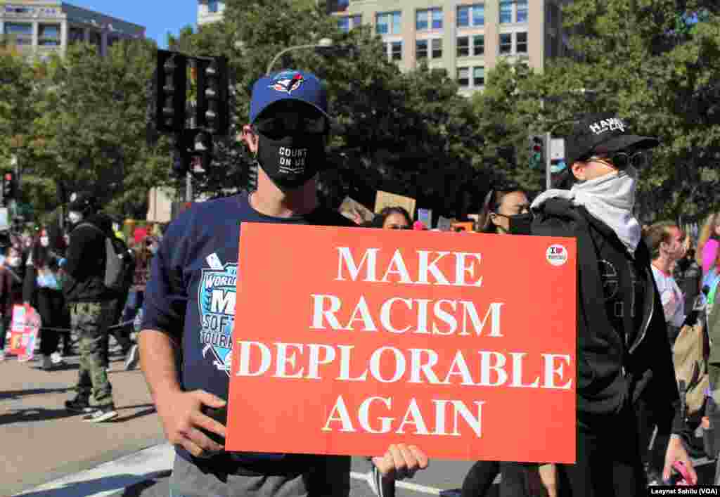 Um homem exibe um cartaz que diz "Torna o racismo deplorável outra vez". Marcha das Mulheres, 17 out, 2020