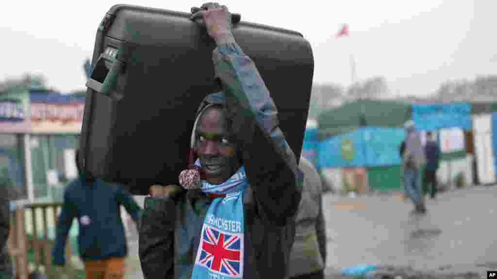 An unidentified migrant carrying his luggage leaves a makeshift camp known as "the jungle" near Calais, northern France, to register at a processing center,Oct. 24, 2016. 