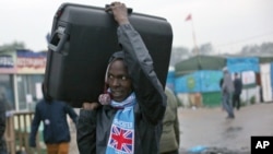 An unidentified migrant carrying his luggage leaves a makeshift camp known as "the jungle" near Calais, northern France, to register at a processing center,Oct. 24, 2016. 