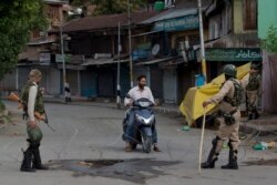 FILE - Indian paramilitary soldiers turn back a Kashmiri motorist near a temporary check point during lockdown in Srinagar, Aug. 18, 2019.