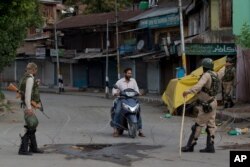 Indian paramilitary soldiers turn back a Kashmiri motorist near a temporary check point during lockdown in Srinagar, Aug. 18, 2019.