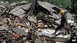 A rescuer walks on the rubble of houses in an area affected by an earthquake in Kalibening, Central Java, Indonesia, April 19, 2018. 