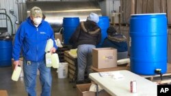 Employees at a new hand sanitizer factory work to load and manufacture product at the facility in Bismarck, N.D., where a number of businesses have switched gears amid the coronavirus outbreak to make products in short supply.