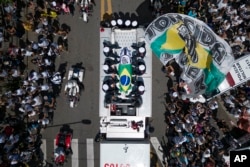 Pele's coffin, draped in the Brazilian flag, is carried through the streets of Santos, Brazil, Tuesday, Jan. 3, 2023. (AP Photo/Matias Delacroix)