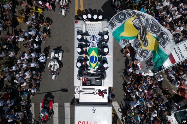 Pele's coffin, draped in the Brazilian flag, is carried through the streets of Santos, Brazil, Tuesday, Jan. 3, 2023. (AP Photo/Matias Delacroix)