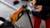 FILE - A worker at a state-owned Pertamina petrol station holds money as a motorcycle is filled with subsidised fuel in Jakarta, Oct. 31, 2014. 