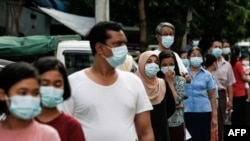 People wearing face masks amid concerns over the spread of the COVID-19 coronavirus wait in line for health check-ups in Yangon on May 17, 2020. (Photo by Sai Aung Main / AFP)