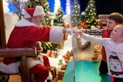 Julianna, 3, and Dylan, 5, Lasczak visit with Santa through a transparent barrier at a Bass Pro Shop in Bridgeport, Conn., Nov. 10, 2020.