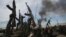 Rebel fighters hold up their rifles as they walk in front of a bushfire in a rebel controlled territory in Upper Nile State, South Sudan, Feb. 13, 2014. 