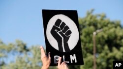 A protester holds up a Black Lives Matter sign outside the police station in Florissant, Mo., June 10, 2020.