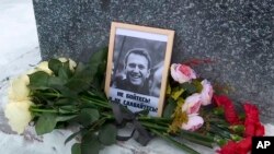 Esta imagen tomada de un video, muestran las flores y una foto del líder opositor Alexei Navalny depositados por su madre, Lyudmila Navalnaya, en su memorial en un monumento a las víctimas de la represión política, en Salekhard, el 20 de febrero de 2024. 