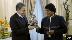 El presidente boliviano Evo Morales, derecha, regala una máscara de diablo al ex primer ministro español José Luis Rodríguez Zapatero en el palacio de gobierno en La Paz, Bolivia, el domingo 24 de junio de 2018. Morales dijo el jueves 5 de julio de 2018 que se encuentra bien y que espera ser dado de alta tras ser operado de un pequeño tumor en una clínica de La Paz. 