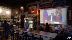 A few visitors and staff of the pub watching the broadcast of Russian President Vladimir Putin addresses Russian citizens on the State Television channels in Moscow, Russia, March 25, 2020. 