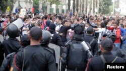 FILE - Cairo University students who support the Muslim Brotherhood and ousted Egyptian President Mohamed Morsi shout slogans against the military and Interior Ministry in front of riot police at the main gate of the university, Cairo, Nov. 24, 2013.